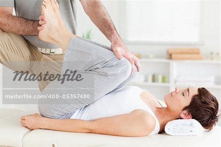 A chiropractor is stretching a woman's legs