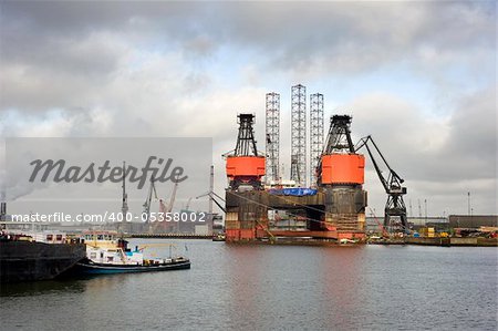 The dismantling of an oil rig at a dry dock in the midst of a busy commercial harbor