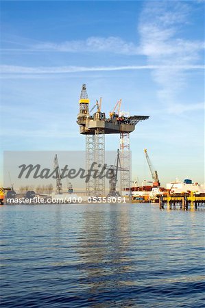 An oil rig is being constructed in a harbor area, to be towed to sea after completion.