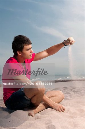 man in red shirt sitting on the beach