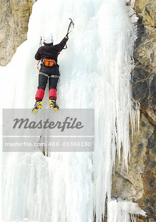 Young man, ice climbing an attractive route.