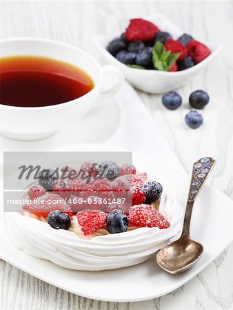 Fresh meringue with thick cream and fruits on a plate
