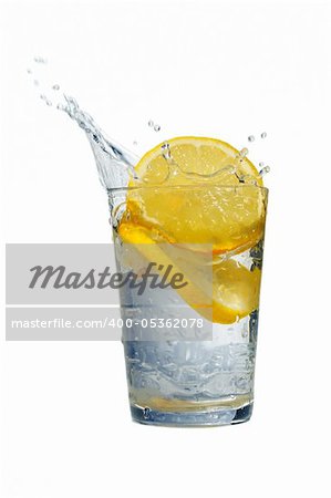 Glass of fresh water with falling lemons isolated on white