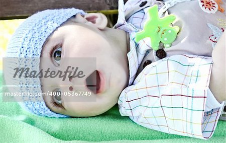 adorable baby boy lies on  green  blanket in park. Summer