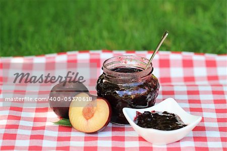 Jar of plum jam and some plums on the napkin