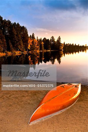 Canoe on beach at sunset on lake shore