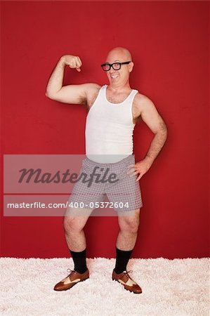 Funny bald muscular man shows off his biceps over maroon background