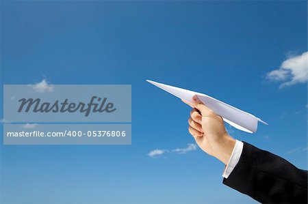 hand of Businessman letting an airplane made of paper fly over blue sky