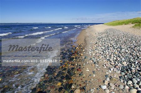 Light waves wash a shore of sand and rounded rocks at Whitefish Bay on Michigan’s Upper Peninsula.