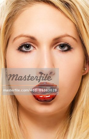 beautiful blonde woman licking chocolate from her chocolate covered lips on white background