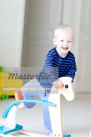 happy toddler is about to sit on the horse