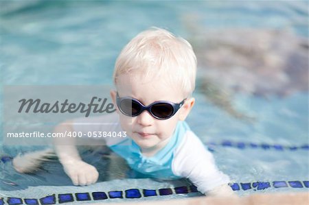adorable toddler in sunglasses having fun in the pool