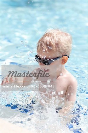 adorable toddler in sunglasses splashing in the pool