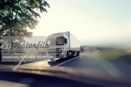 European truck speeding on freeway with colorful ambient colors and blurred motion. View from another passenger car.