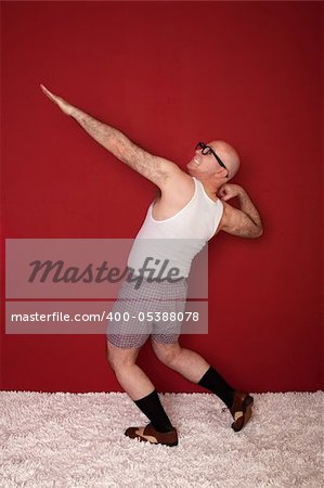 Funny bald Caucasian man shows off his biceps over maroon background