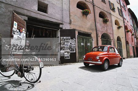 Red Fiat Car And Bicycle Parked In Street
