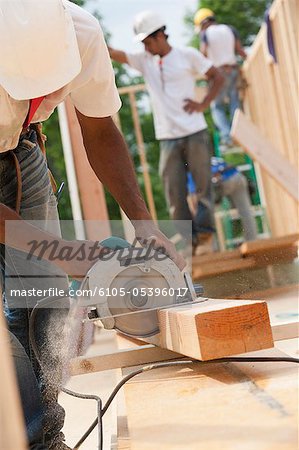Carpenter cutting a joist with a circular saw