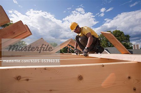 Carpenter marking spacing of rafters with a pencil
