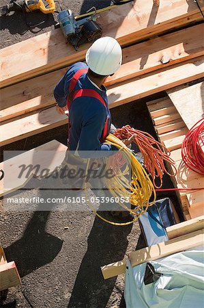 Carpenter holding coiled power cords and air hose