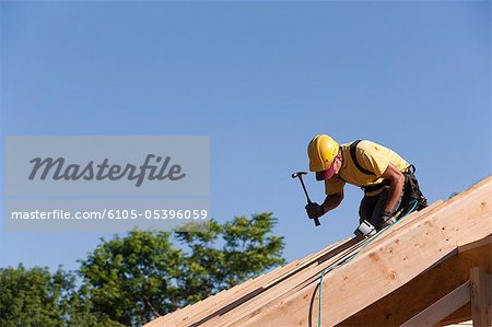Carpenter hammering on roof rafters