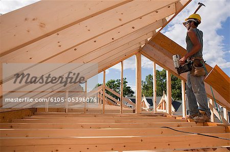 Carpenter hammering on roof rafters