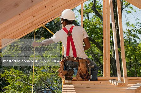 Carpenter measuring roof rafters