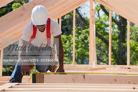 Carpenter measuring joists and beams