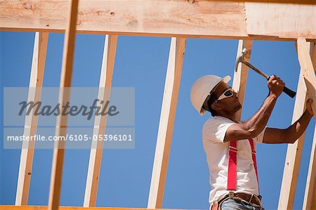 Carpenter hammering on roof frame