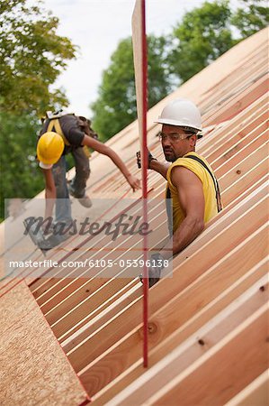 Carpenters lifting a roof panel  onto place on a roof