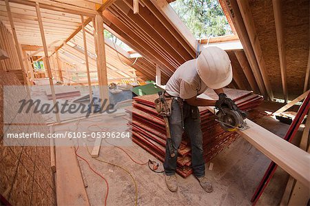 Zimmermann mit einer Kreissäge auf dem Dach Sparren in einem Haus im Bau Zimmermann mit einer Kreissäge auf dem Dach Sparren in einem Haus im Bau
