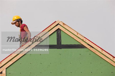 Hispanic carpenter working on the roof of a house under construction