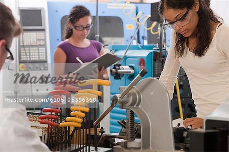 Engineering professor and students working on a CNC machine