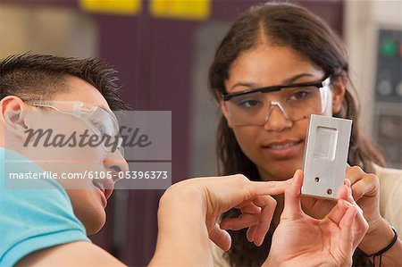 Engineering students examining a machined part in a laboratory