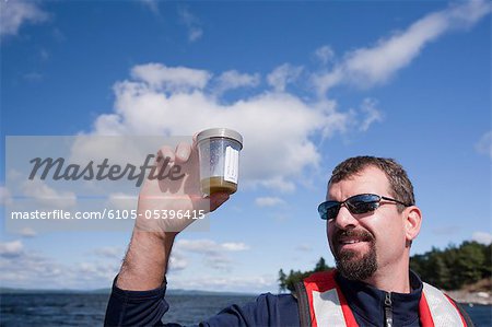 Scientist collecting samples of algae in a boat