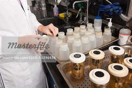 Scientifique d'étiqueter les bouteilles chimiques en laboratoire de l'usine de traitement de l'eau