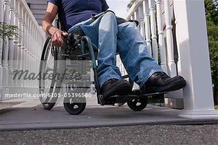 Man with spinal cord injury in a wheelchair on the top of home access ramp