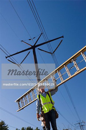 Engineer carrying a ladder to install equipment on power poles