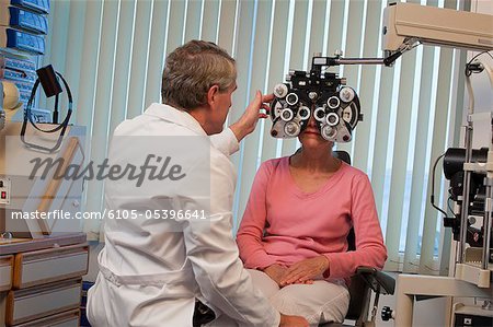 Ophtalmologue examinant les yeux d'une femme avec un réfracteur