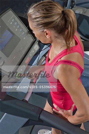 Frau, stehend auf einem Laufband in einem Fitnessstudio
