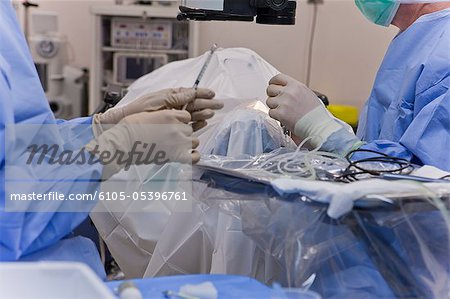 Surgical technologist passing antibiotic to doctor during cataract surgery