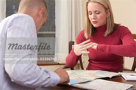 Woman signing the word 'Beach' in American Sign Language while looking at a map