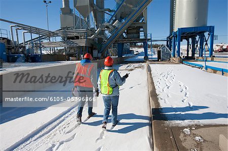 Two engineers examining at an industrial plant in winter