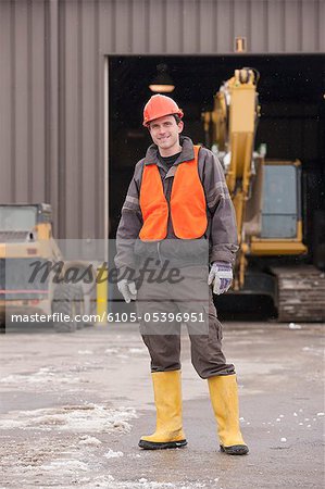 Transportation engineer standing at heavy construction equipment garage