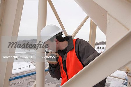 Engineer talking on a walkie-talkie while inspecting a tank tower