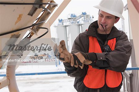 Engineer putting on work gloves on tank tower inspection platform