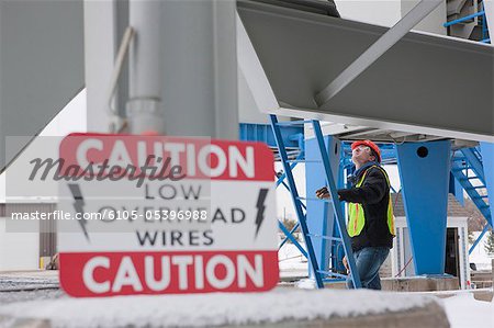 Warnschild an einer Industrieanlage mit einem Ingenieur erklimmen einer Leiter