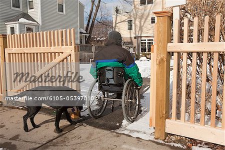 Femme avec sclérose en entrant dans la maison avec un chien d'assistance en hiver