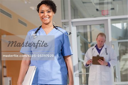 Portrait d'une femme infirmière souriant avec un médecin de sexe masculin debout derrière elle