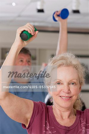 Man and woman exercising with dumbbells in a health club