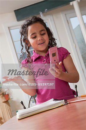 Hisoire jeune fille à l'aide d'un téléphone portable tout en faisant des travaux scolaires